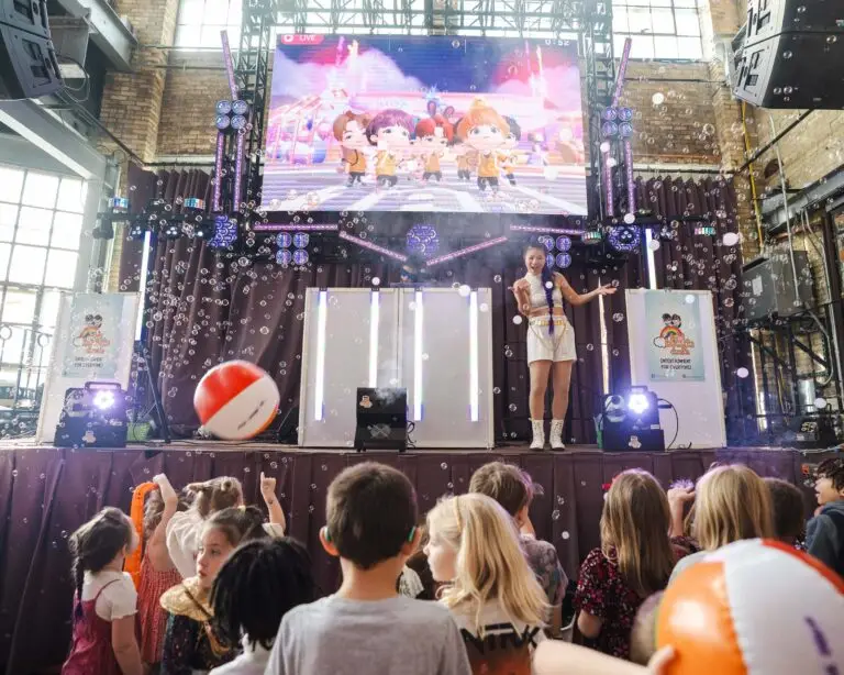 A Kid Boogie Down host leads a crowd of kids from the stage under a video wall and falling bubbles at The Cooperage in Milwaukee.